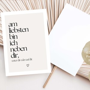 May include: A beige postcard with black text that reads "am liebsten bin ich neben dir, unter dir oder auf dir." A blank white postcard is next to it. The postcard is made of 400g/m2 premium paper and is a DIN A6 postcard.