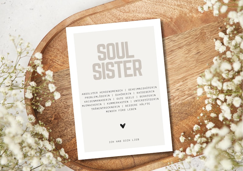 May include: A beige card with the words "Soul Sister" in large, bold, gray letters. The card has a list of words describing a soul sister, such as "absolute heart person", "home protector", "problem solver", "listener", "advisor", "crisis manager", "good soul", "counselor", "cheerleader", "confidant", "supporter", "tear dryer", "better half", and "person for life". The card also has a small black heart and the words "I love you" in black text.