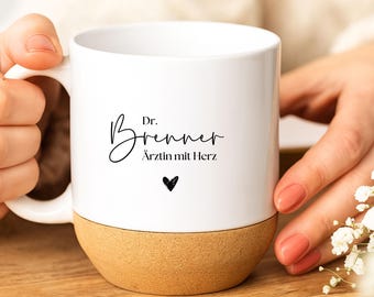 May include: White ceramic mug with a natural cork base. The mug features the name "Dr. Brenner" in elegant script, along with the phrase "Ärztin mit Herz" and a small black heart. A perfect gift for a doctor.
