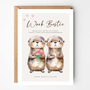 May include: A greeting card with a watercolor illustration of two otters. The card reads "Work Bestie" with text below in German. One otter holds a bouquet of pink flowers. The card is in a brown envelope.