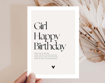 May include: A birthday greeting card with the words "Girl Happy Birthday" in a bold, black font. The card has a cream-colored background with a small black heart at the bottom. The card is held by a hand, with dried flowers in the background.