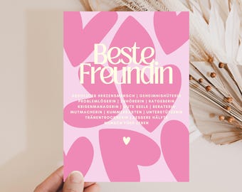 May include: A rectangular card with a light pink background featuring multiple dark pink heart shapes. The text "Beste Freundin" is printed in large cream letters, followed by a list of German words including "Herzensmensch" and "Zuhörerin".