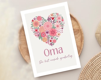 May include: A floral heart design on a white card. The heart is filled with pink, peach, and purple flowers and green leaves. The word "Oma" is written in pink script, with the phrase "Du bist einfach großartig" below it.