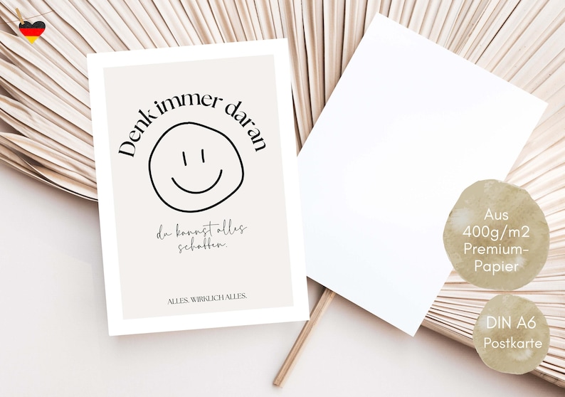 May include: A beige postcard with the text "Denk immer daran" and a smiley face. The postcard also includes the text "da kannst alles schaffen" and "ALLES WIRKLICH ALLES". A blank white postcard is next to it.