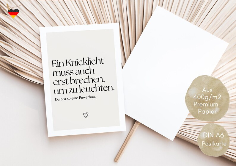 Puede incluir: Una postal blanca con una cita en blanco y negro en alem&aacute;n: "Ein Knicklicht muss auch erst brechen, um zu leuchten." La cita va seguida del texto "Du bist so eine Powerfrau." y un peque&ntilde;o s&iacute;mbolo de coraz&oacute;n. La postal est&aacute; sobre un fondo marr&oacute;n claro.