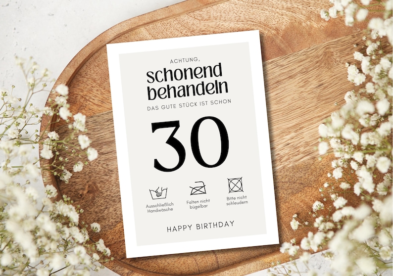 May include: A white card with black text that reads "ACHTUNG, schonend behandeln DAS GUTE ST&Uuml;CK IST SCHON 30" and has three laundry care symbols below the number 30. The symbols indicate that the item should be hand washed, not ironed, and not machine dried. The card also says "HAPPY BIRTHDAY" at the bottom.