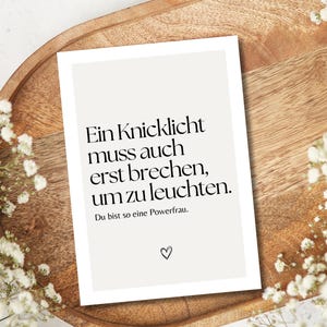 Puede incluir: Una tarjeta blanca con texto negro que dice "Ein Knicklicht muss auch erst brechen, um zu leuchten. Du bist so eine Powerfrau." Hay un peque&ntilde;o s&iacute;mbolo de coraz&oacute;n en la parte inferior de la tarjeta.