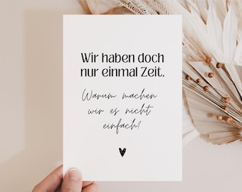 May include: A white card with black text that reads "Wir haben doch nur einmal Zeit. Warum machen wir es nicht einfach!" with a small black heart at the bottom.