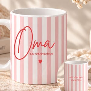 Puede incluir: Una taza de cerámica blanca con rayas verticales de color rosa claro. El frente muestra el texto rojo Oma, la frase Du bist einfach toll y un pequeño corazón rojo. Un recuadro muestra la misma taza con el texto Hier steht dein Wunschtext.