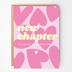 Può includere: Un biglietto d'auguri con sfondo rosa chiaro caratterizzato da un motivo di cuori rosa a tinta unita. Il testo "new chapter" è stampato in grandi lettere in grassetto color crema, con il testo più piccolo "it's going to be amazing" sotto.