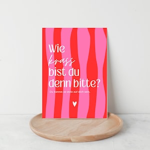 May include: A rectangular greeting card featuring a vertical wavy striped pattern in alternating shades of bright red and hot pink. The card displays the white text "Wie krass bist du denn bitte?" followed by "Du kannst so stolz auf dich sein." and a small white heart icon.
