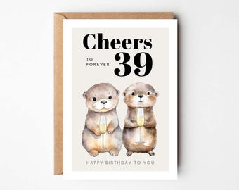 May include: A birthday card with two otters holding champagne glasses. The card says "Cheers to forever 39 Happy Birthday to You".