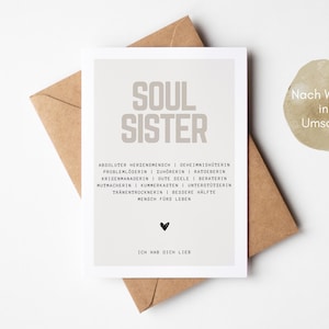 May include: A light brown card with the text "SOUL SISTER" in large, bold, gray letters. The card has a light gray background and includes a list of qualities that describe a soul sister. The text "ICH HAB DICH LIEB" is at the bottom of the card.