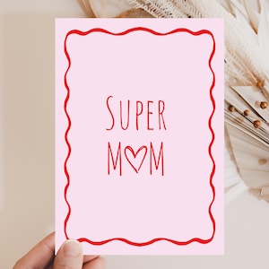 Könnte beinhalten: Eine rechteckige Grußkarte mit hellrosa Hintergrund und einem roten, wellenförmigen Rand. Der Text "SUPER MOM" ist mittig in Rot aufgedruckt, wobei ein rotes Herz den Buchstaben "O" im Wort "MOM" ersetzt. Die Karte hat ein klares Design.