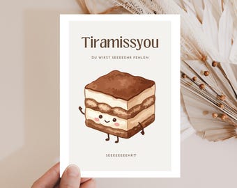 Può includere: Un biglietto di auguri con un'illustrazione di tiramisù a cartoni animati. La carta ha le parole "Tiramissyou" e "DU WIRST SEEEEEEHR FEHLEN" in testo marrone. Il tiramisù ha una faccia sorridente, braccia e gambe. Il fondo della carta dice "SEEEEEEEHR".