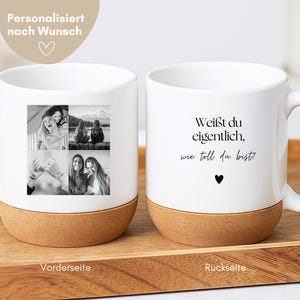 Op de afbeelding: Twee witte keramische mokken met kurken bodems worden getoond. Eén mok heeft een collage van zwart-witfoto's, de andere heeft de tekst "Weißt du eigentlich, wie toll du bist!" met een hartsymbool.