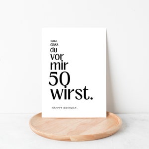 May include: A white card with black text that reads "Danke, dass du vor mir 50 wirst. Happy Birthday."