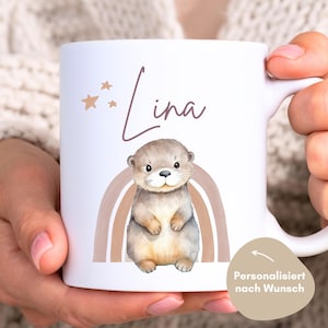 May include: White ceramic mug with a brown and tan rainbow, a cartoon otter, and the name "Lina" in pink script. The mug is personalized with the name "Lina".