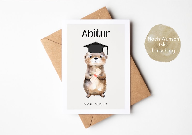 May include: A graduation card featuring a cartoon otter wearing a graduation cap and holding a diploma. The card has the text "Abitur" and "You Did It" on it. The card is on a brown envelope. The text "Nach Wunsch inkl. Umschlag" is on the envelope.