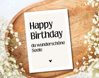 May include: A white card with black text that reads "Happy Birthday du wunderschöne Seele" with a small black heart at the bottom.