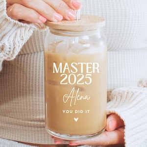 Könnte beinhalten: Ein klares Glasgefäß mit einem Holzdeckel, gefüllt mit Eiskaffee. Auf dem Gefäß steht der Text "MASTER 2025 Alena YOU DID IT".