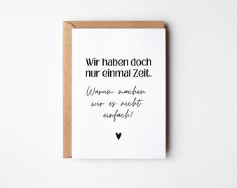 May include: A white card with black text that reads "Wir haben doch nur einmal Zeit. Warum machen wir es nicht einfach!" with a small black heart at the bottom.