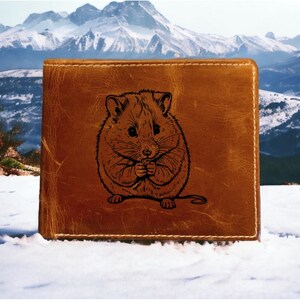 May include: A brown leather wallet with a laser-engraved image of a hamster holding a small object in its paws.