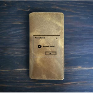 May include: A brown leather wallet with a computer error message on the front that says "Access Denied" with an "OK" button.