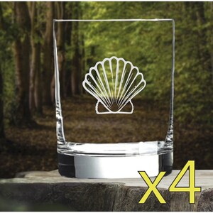 May include: Set of four clear glass tumblers with a white seashell design etched on the front. The tumblers have a silver base and are displayed on a wooden surface. The text "x4" is printed in yellow on the right side of the image.