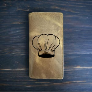 May include: A brown leather wallet with a chef's hat and the word "Chef" engraved on it.