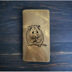 May include: A brown leather wallet with a laser-engraved image of a hamster holding a small object in its paws.