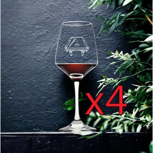 Puede incluir: Un juego de cuatro copas de vino de cristal transparente, cada una con un grabado blanco de una mesa de billar con un taco y un juego de bolas. Las copas contienen un líquido rojo oscuro y presentan un tallo fino y una base ancha.