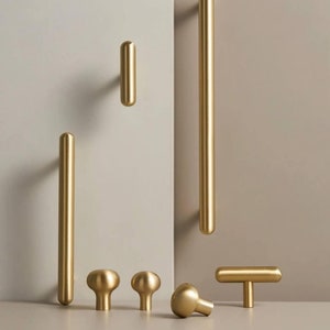 May include: A set of six gold-toned cabinet hardware pulls and knobs. The set includes three different styles: a long bar pull, a short bar pull, a T-shaped pull, and three round knobs.
