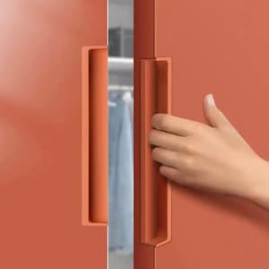 Könnte beinhalten: Nahaufnahme eines Paares orangefarbener Schranktüren mit einem langen, rechteckigen Griff an jeder Tür. Eine Hand greift nach dem Griff an der rechten Tür.