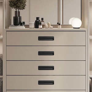 Könnte beinhalten: Eine hellbeige Kommode mit fünf Schubladen und schwarzen rechteckigen Schubladengriffen. Die Kommode ist im modernen Stil gehalten und hat ein minimalistisches Design.