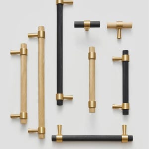May include: Assortment of cabinet hardware in gold and black finishes. The hardware includes knobs, pulls, and bar pulls. The knobs and pulls have a textured diamond pattern.