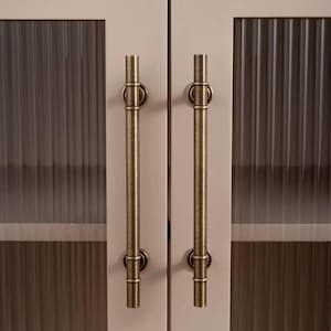 May include: Two cabinet doors with frosted glass panels and antique brass handles. The doors are painted a light pink colour.