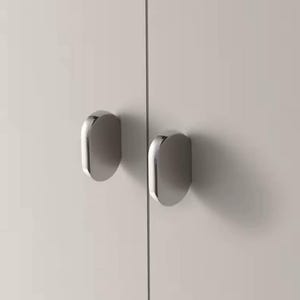 Könnte beinhalten: Zwei silberne, abgerundete Schranktürgriffe sind an einer weißen Schranktür montiert.