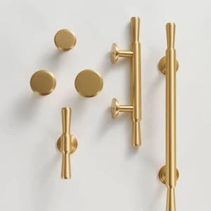 May include: A selection of gold-coloured cabinet hardware, featuring three round knobs, a small handle, and two larger pull handles. The hardware has a sleek, modern design and is set against a white background.