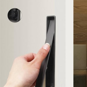 May include: A black flush pull handle for doors and cabinets. The handle is made of metal and has a rectangular shape. The handle is mounted on a white surface.