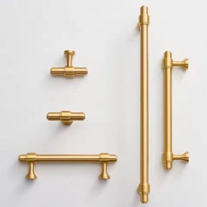 May include: Set of five gold-toned cabinet hardware pulls and knobs. The set includes two long pulls, one short pull, and two knobs.