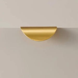 May include: A gold half-circle cabinet pull.