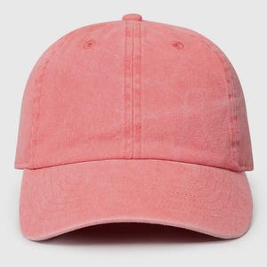May include: A solid pink baseball cap with a slightly distressed look. The cap has a curved brim and a classic six-panel design.