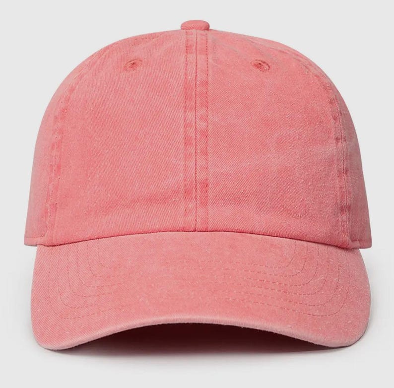 May include: A solid pink baseball cap with a slightly distressed look. The cap has a curved brim and a classic six-panel design.