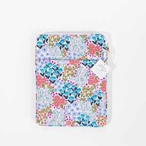 Könnte beinhalten: Eine Tech-Hülle mit Blumenmuster, mit weißem Hintergrund und einem farbenfrohen Muster aus blauen, rosa und orangefarbenen Blumen. Die Hülle hat einen Reißverschluss und ein Etikett mit "Anna Whitlock Co. Tech Sleeve".