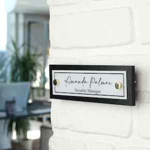May include: Black and white office door sign with gold accents. The sign reads "Amanda Palmer, Security Manager".