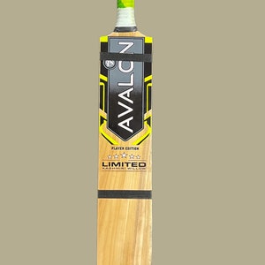 May include: A wooden cricket bat with a light brown blade and a black grip. The handle is wrapped in green and white tape. The bat features the text "AVALON" and "LIMITED KASHMIRI WILLOW".