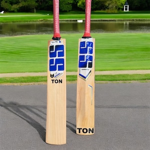 May include: Two wooden cricket bats with blue and gold accents. The bats have the word "TON" printed on them.