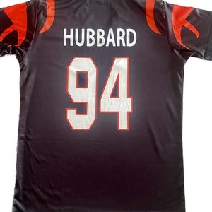 May include: Black jersey with red and white accents. The back of the jersey has the name "HUBBARD" and the number "94" in white.