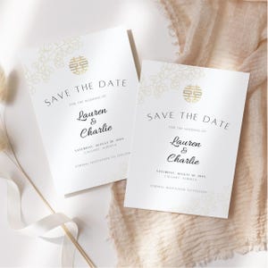 May include: Two white "Save the Date" cards with gold floral details and text. The cards read "Save the Date" and include the names "Lauren & Charlie" and the date "Saturday, August 18, 20XX, Calgary, Alberta."